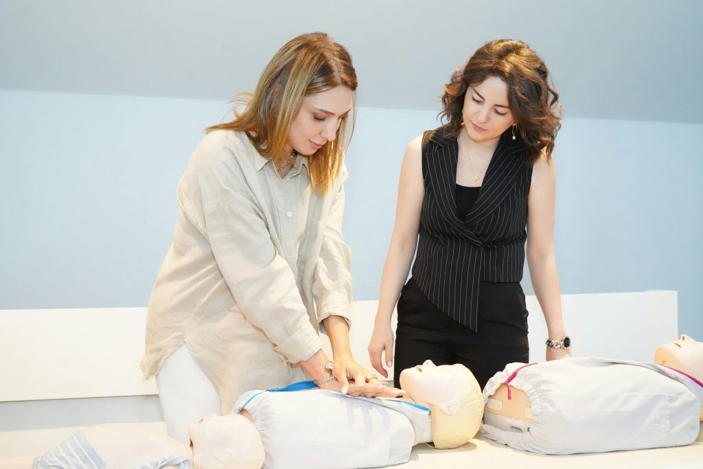 Two women learning CPR techniques on training mannequins during a healthcare workshop.